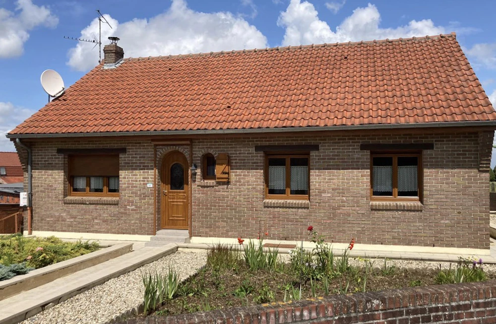 Extérieur d'une maison individuelle de plain-pied avec jardin aménagé, allée dallée et plantations florales
