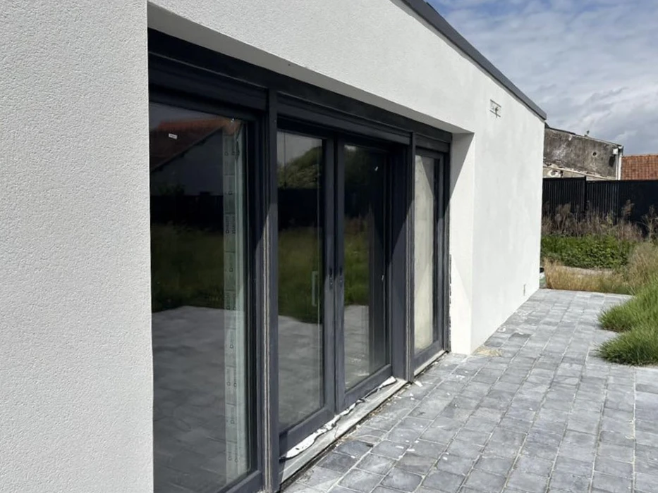 Terrasse extérieure d'une maison moderne avec baie vitrée coulissante à trois vantaux ouverte