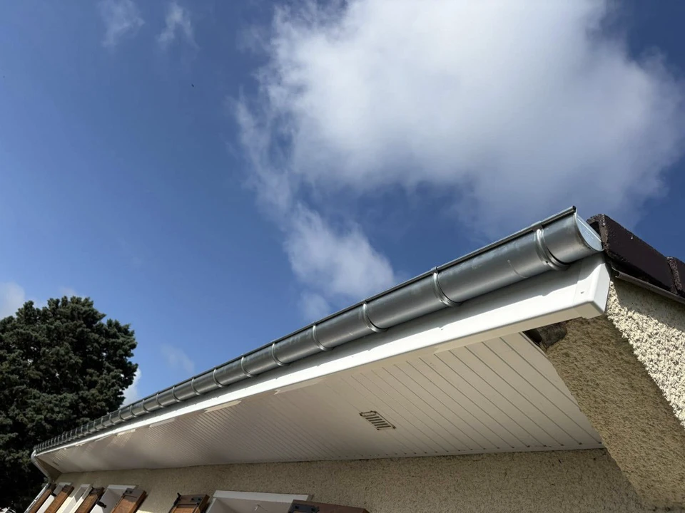 Extérieur résidentiel avec maison contemporaine à deux étages, façade blanche, toiture tuiles grises, terrasse avec mobilier de jardin, pelouse entretenue, environnement pavillonnaire