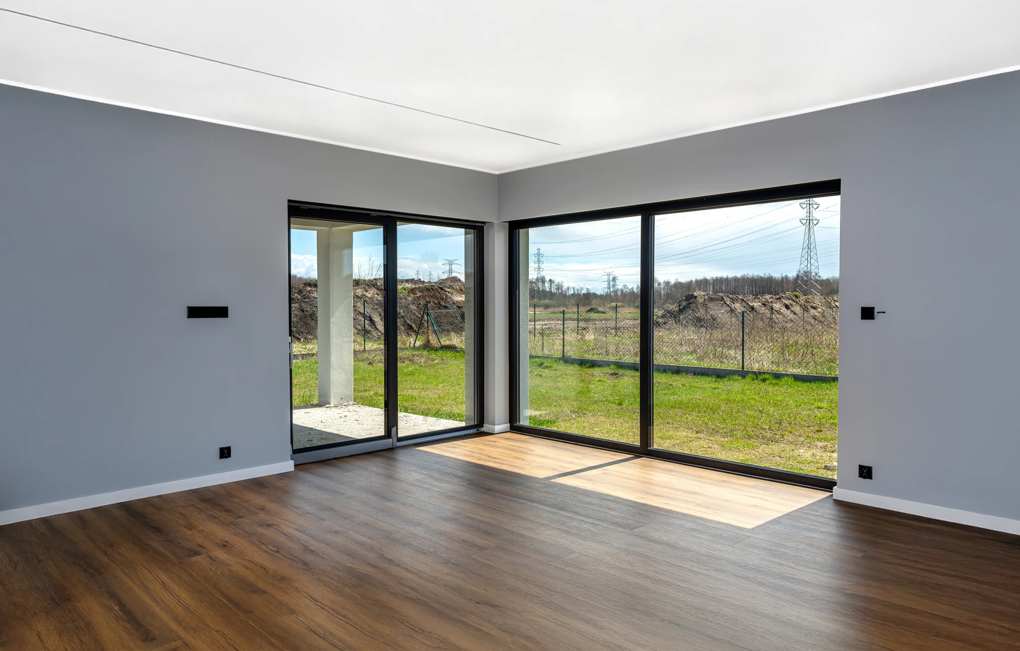 Façade extérieure de maison résidentielle en briques rouges avec porte d'entrée blanche à panneau vitré, escalier en briques, garde-corps métallique noir, fenêtres blanches à guillotine et jardinières décoratives avec végétation